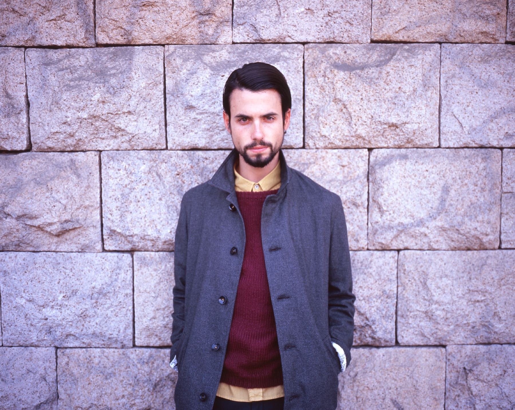 EACH OF ONE grey wool coat against a stone wall